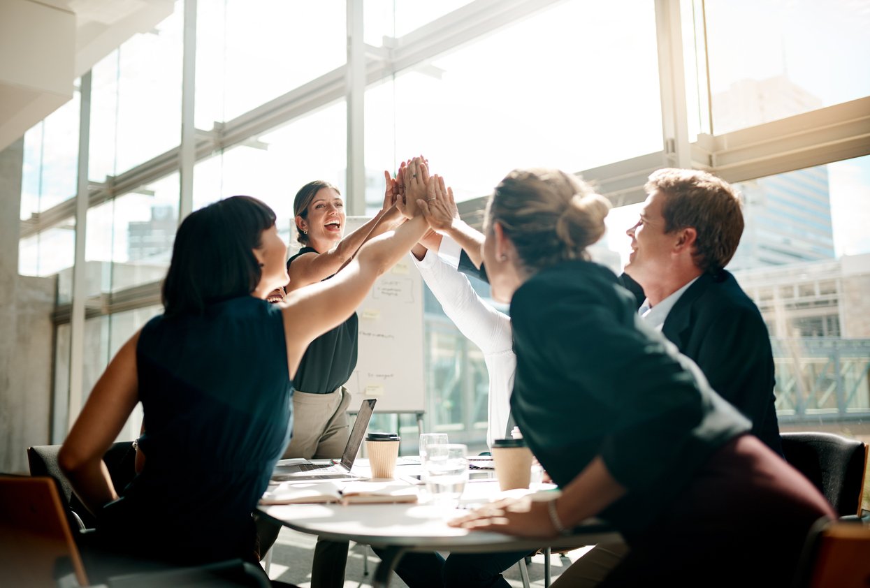 Group of diverse business professionals in an office giving a high five to each other.