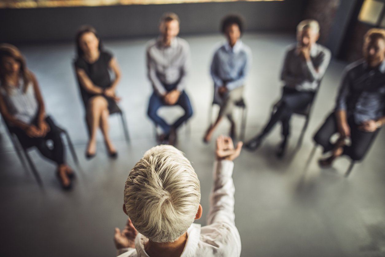 Female coach conducting an executive coaching session to a group of professionals.