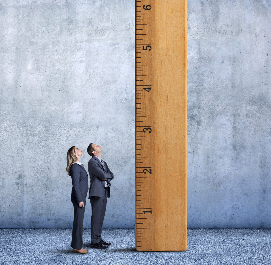 Business owners standing beside a wooden ruler, showing a concept of business scaling.