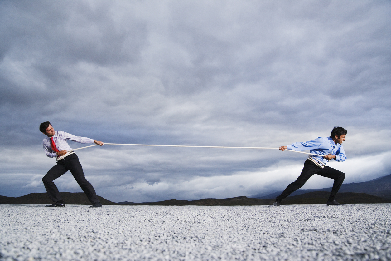 A concept of winning against your competitors - businessmen playing a game of tug of war.